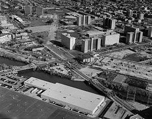 A black-and-white photograph of a neighborhood; it is taken from an aerial point of view.