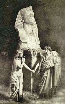 Stage photograph showing actor as Julius Caesar and actress as Cleopatra in Egyptian setting