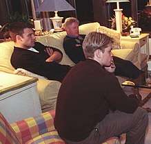  Bill Clinton, Ben Affleck and Matt Damon sit on two sofas while looking towards a television screen