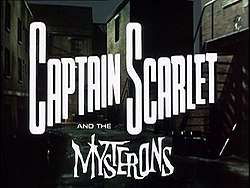 In bold, white letters, the words "Captain Scarlet" are superimposed on the backdrop of a derelict, night-time alleyway. Added at the bottom of the picture are more words, "and the Mysterons", the last of which is in white, spiky lettering. The full title is thus revealed to be "Captain Scarlet and the Mysterons".