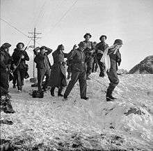 four Germans one with a white flag surrounded by British troops crossing a snow-covered landscape