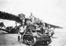 Soldiers sitting on a small armoured vehicle in front of a grounded aircraft