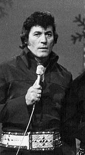 A dark-haired man holding a microphone