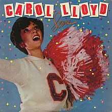 Lloyd stands in a cheerleading outfit and holds pom-poms in front of a blue background displaying the album's title.