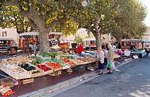 Outdoor scene showing market stalls full of a bright fruit and vegetables