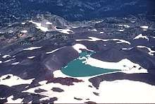 A snow-covered lake surrounded by dark glacial till