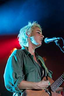 Cat Power playing guitar and singing into a microphone