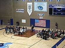 Students in gymnasium holding 9/11 ceremony with flags