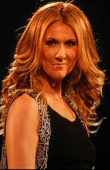 A woman with curly blonde hair wearing a black dress.