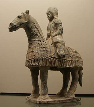 Photo of a terracotta statue showing a horse and its rider, both decked in lamellar armour