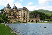 Large chateau on a man-made lake, surrounded by visitors