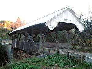 Wooden covered bridge with open sides and X-shaped beams