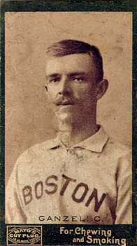 A sepia-toned photograph of a mustachioed man wearing a white baseball jersey