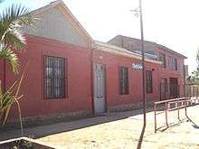 Colonial red building. The front of the building says "Charly's School".