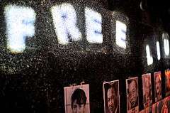 Row of portraits, and lights spelling out the words 'FREE LIU'