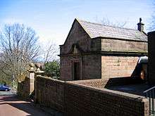 A small sandstone building with a slate roof