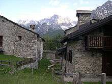 Two stone houses, with mountain in background
