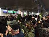 Crowd of protesters inside O'Hare International Airport, some holding signs.