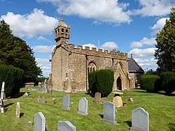 Stone building with small bell tower. In the foreground are gravestones.