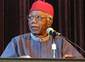 Achebe in blue cap at lectern