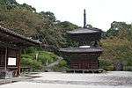 Small wooden two-storied pagoda shaped building with a square base and a round upper floor.