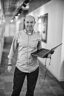 Black and white photograph of a man holding a laptop.