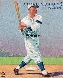 A baseball card image of a light-skinned man in a white baseball uniform swinging a blond-colored baseball bat, which he holds over his right shoulder
