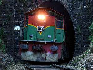 Red-and-green locomotive emerging from a tunnel