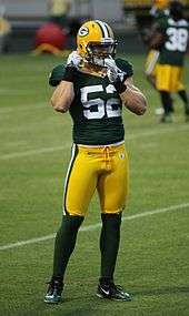 A picture of Clay Matthews III on the filed in uniform adjusting his chin strap