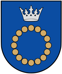 A coat of arms depicting a circle for which the boundary is itself made up of beige circles all under a silver crown on a blue background