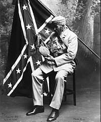 Confederate soldier posing in front of official Confederate battle flag