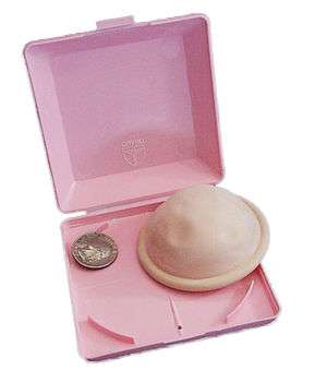 A diaphragm contraceptive device, shown with its box, and a coin (it is about 3 times wider than the quarter).