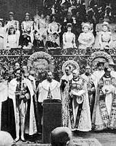 Black-and-white photograph of large altar dishes standing on a table in front of the royal box during a coronation