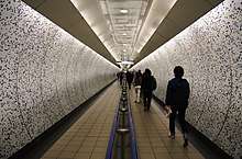 A view along a passage with curved walls covered in mosaic tiling and a semi-circular ceiling