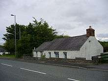 white painted single storey cottage with slate rook