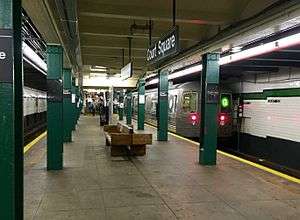 The underground Court Square station is the "G" train's northern terminus. There are two tracks in the station, one on each side of the center platform, with a "G" train on the right-hand track.