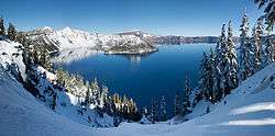 A panorama shot shows Crater Lake in the winter season. Its surroundings are covered in snow