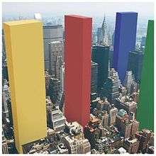 A city with four colored blocks (from left to right: Yellow, Red, Blue and Green) much taller than the regular buildings