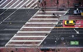 Aerial view of a crosswalk crossing a street at a skewed angle, marked with simple white parallel lines, in San Francisco