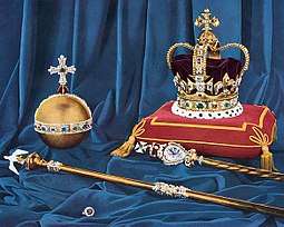 Colour photograph taken in 1952 of the regalia in front of a blue drape. St Edward's Crown rests on a red cushion that has gold trimming.