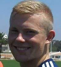 Head of a young blond man smiling.