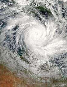 Satellite view of a large, well-developed tropical cyclone near northern Queensland. A pronounced, yet cloud-filled eye and curved rainbands mark the characteristics of a mature storm.