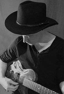 man playing guitar with hat on