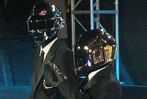 Two men wearing grey jumpsuits and robot helmets.