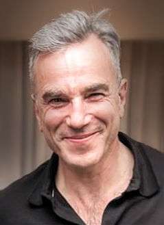 A smiling man with grey hair wearing a black collared shirt.