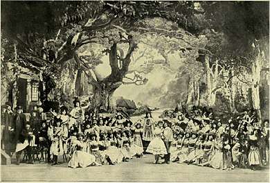 photograph of a large ballet troupe posed on a large stage with an elaborate woodland set