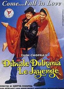 The Dilwale Dulhania Le Jayenge theatrical release poster shows a man in a black leather jacket and blue jeans holding over his shoulders a woman in a red wedding dress. A caption on top reads "Come&nbsp;... Fall in Love".
