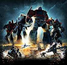 Poster showing Generation 1 (G1) Optimus Prime, G1 Megatron, G1 Starscream, and movie versions of Sideswipe, Jetfire and Soundwave. Four robots are oversized for the poster, and are shown over an Egyptian city.  Below Soundwave is shown in both robot and vehicle modes on the left, while Jazz and Jetfire are shown in robot mode on the right.