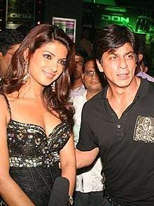 A photograph of Priyanka Chopra and Shah Rukh Khan looking forward, smiling and posing for the camera