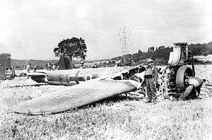 A picture of a twin engine bomber aircraft lying in a field with its front end burnt out